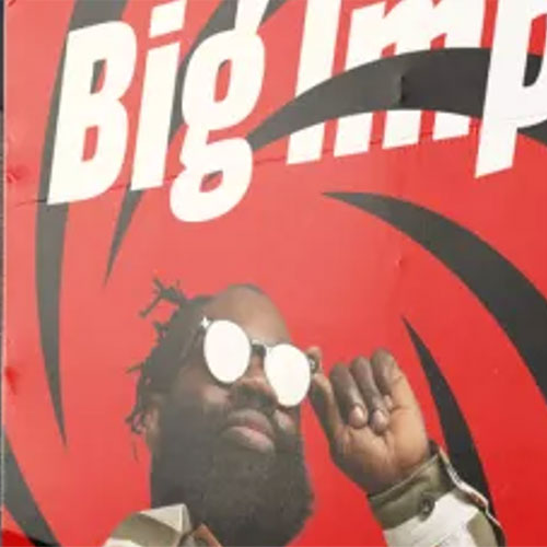 Ein Mann mit Bart und Sonnenbrille posiert vor einem kräftigen rot-schwarzen Hintergrund mit großem weißem Text, auf dem teilweise Big Imp steht.